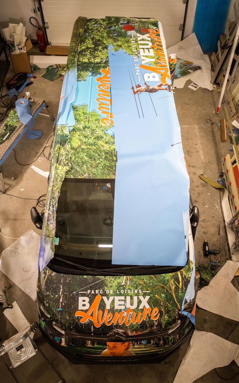 Pose d'un adhésif pour un marquage total covering sur un véhicule Bayeux aventure